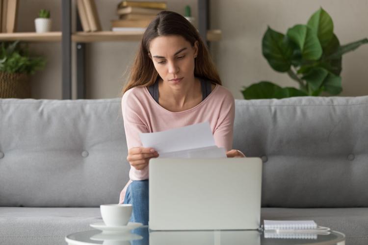 Serious woman sitting on couch reading letter