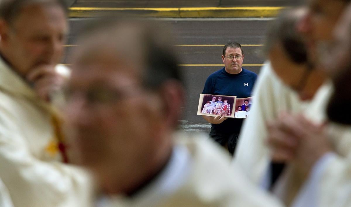 Abuse survivor stands alone outside Cathedral Basilica during Mass of Reparation