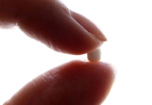 An illustration picture shows a woman holding a pill at her home in Nice