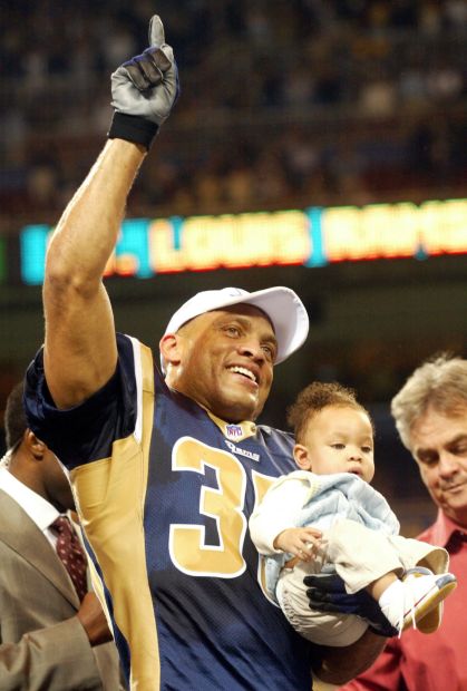 St. Louis Rams' Aeneas Williams, holds his son, Lazarus, as he