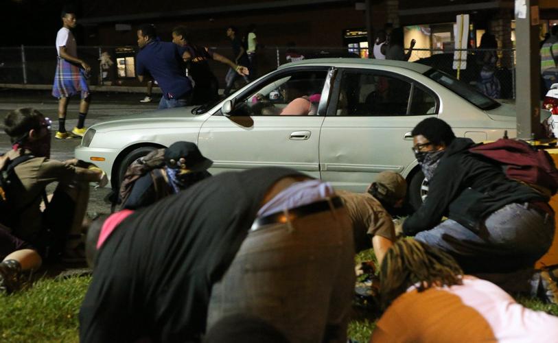 Protesters take cover when gunfire erupts out on West Florissant Avenue
