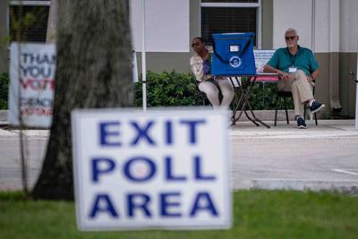 Vote-by-mail attendants sit with a dropbox at the early voting polling site at the Greenacres Community Center in Greenacres,