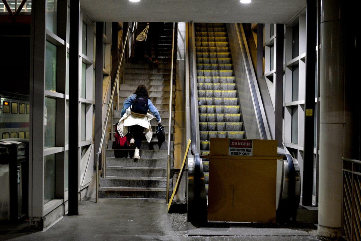 A woman carries a suitcase up the stairs next to a broken escalator at the Hamilton Train Station on Feb. 6, 2025, in Hamilton, N.J.