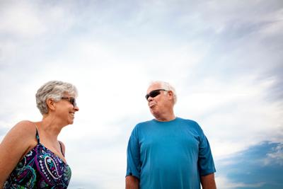 Low angle view of senior couple standing against cloudy sky
