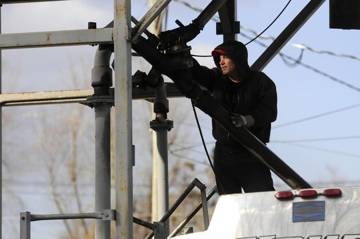 Standing on top of his truck, an oil delivery man with Krupa Oil Company in Suffield, Connecticut, loads his truck in a December 2018 file image.
