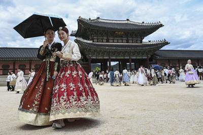 Visitors dressed in traditional Hanbok dresses walk at the Gyeongbokgung Palace in Seoul on June 21, 2026.