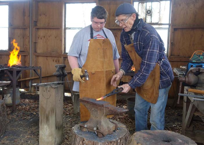 A blacksmith tends the forge fire.