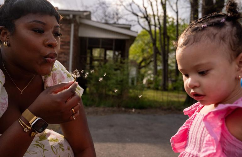 Sydnee McRae shows her 1-year-old daughter, Sevynn, how to blow on a dandelion outside a transitional home for Ella's House in Nashville on Wednesday, April 1, 2026. Ella's House, a nonprofit, supports female college students who are pregnant and parenting