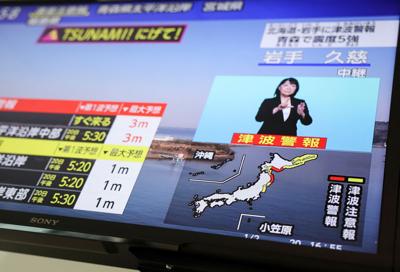 A television screen shows a news report on Japan Meteorological Agency's tsunami warning after an earthquake struck off the northeastern coast of Japan, in Tokyo