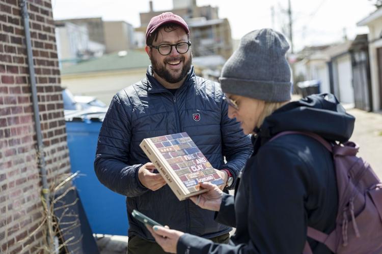 Will Quam sells a copy of his new book "Fire and Clay: How Bricks Reveal the Hidden History of Chicago” after leading one of his neighborhood tours Sunday, April 19, 2026, in Albany Park.