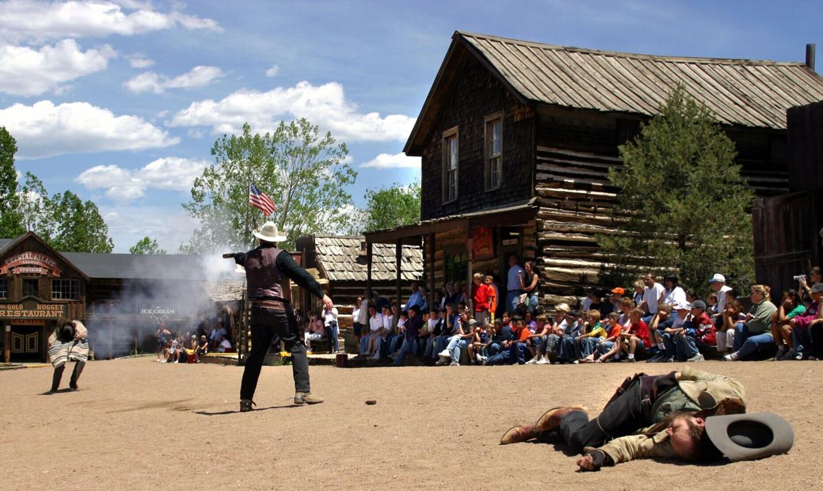 The sheriff of Buckskin Joe Frontier Town, center, dispatches an outlaw during a mock gunfight as a dead cowboy lies in the dust on Main Street Thursday afternoon, May 22, 2003.