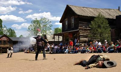 The sheriff of Buckskin Joe Frontier Town, center, dispatches an outlaw during a mock gunfight as a dead cowboy lies in the dust on Main Street Thursday afternoon, May 22, 2003.