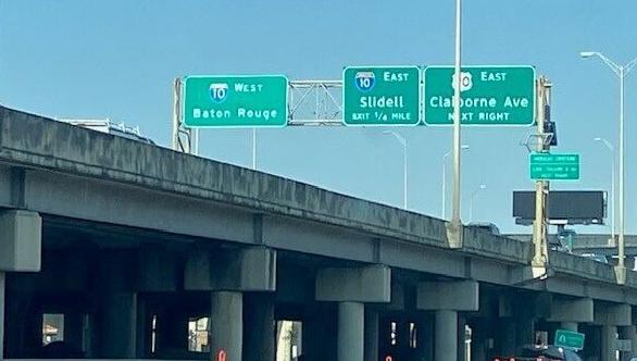 Highway signs above the single unhoused encampment approved by Gov. Landry