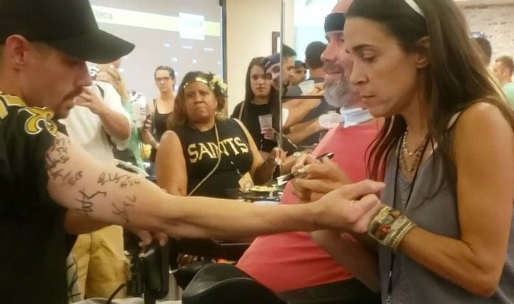 Steve Gleason and wife Michel Varisco sign the arm of 'Signature Saint' Brian Henry