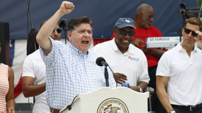 Gov. J.B. Pritzker raises his fist while speaking at the Illinois State Fair in Springfield.
