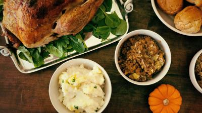 Roast turkey, mashed potatoes, stuffing, and rolls arranged on a table for Thanksgiving.