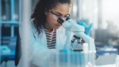 FILE - Scientist looking in microscope, medical, science, laboratory