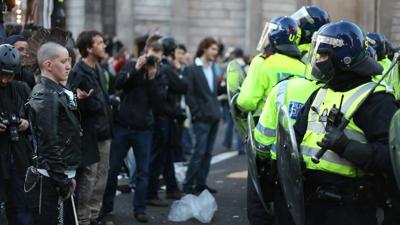 Protester stands in front of police in riot gear during demonstration