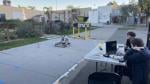 Students monitoring and testing a small robot on a marked outdoor course at a high school.