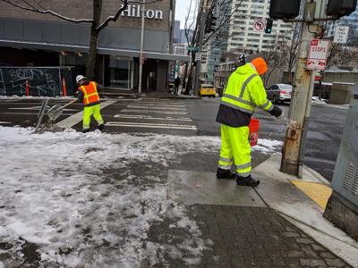 Sidewalk cleared by road worker in special attire, removing snow