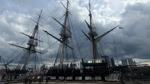 USS Constitution docked in Charlestown beneath a cloudy sky.