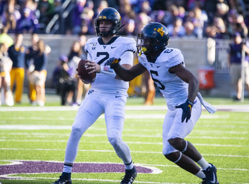 West Virginia quarterback Jarret Doege (left) takes the snap against Kansas State at Bill Snyder Family Stadium on Nov. 16, 2019.