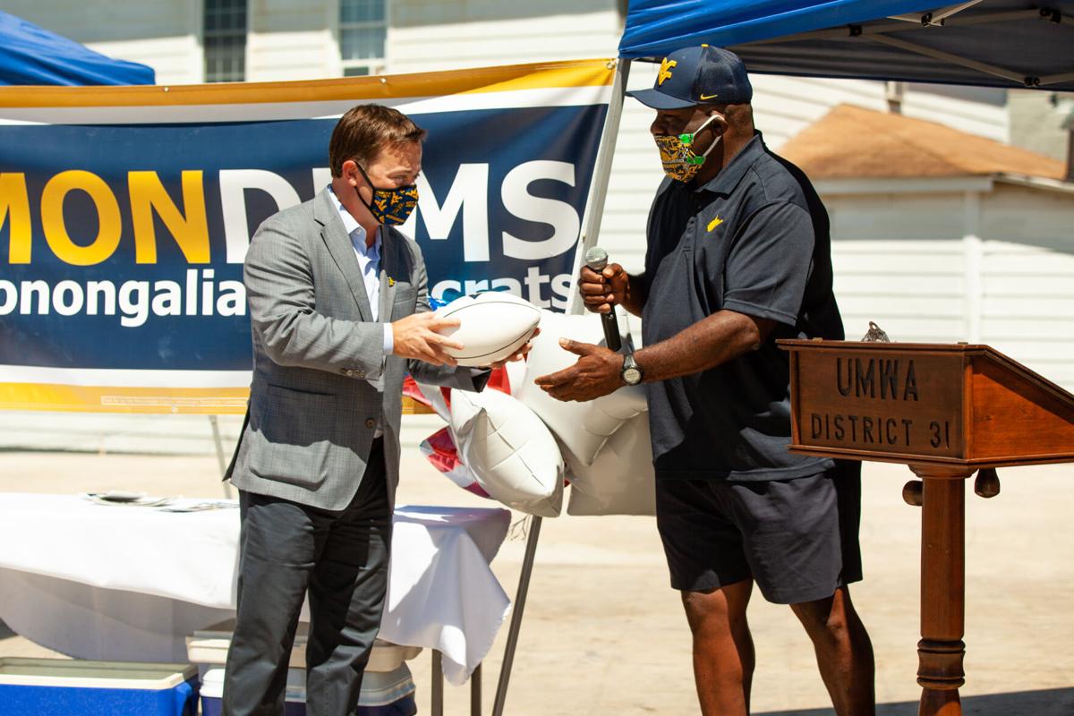 Former Mountaineer football player Major Harris hands a football to Democratic gubernatorial candidate Ben Salango at the ribbon cutting ceremony for the Salango campaign's field office in Morgantown on August 19, 2020 .