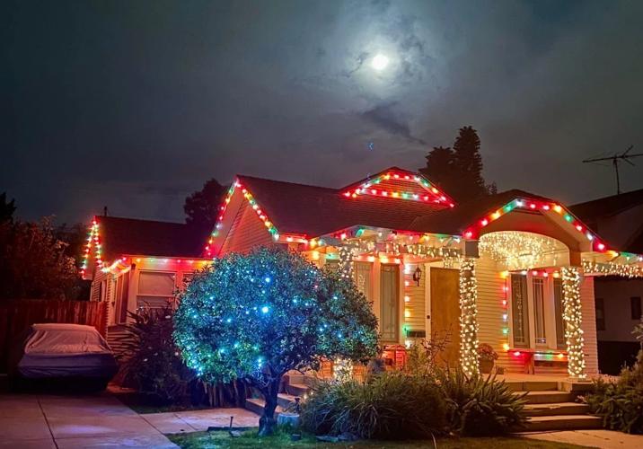 A single-story home in Atwater Village decorated with colorful Christmas lights glows beneath a bright full moon at night.