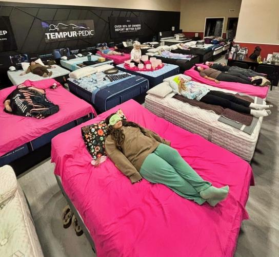 People wear eye shades as they lay atop a selection of mattresses