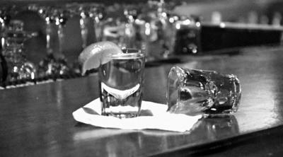 Black and white image of two shot glasses on bar top