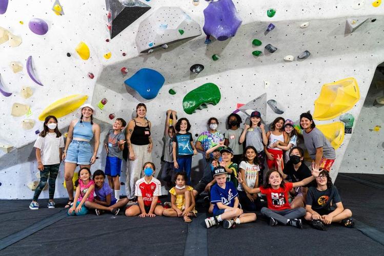 Group of boys and girls gathered in front of an indoor climbing wall at Stronghold Gym