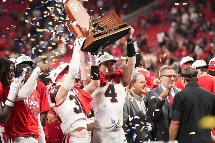 Dec 6, 2025; Atlanta, GA, USA; Georgia Bulldogs tight end Oscar Delp (4) and Georgia Bulldogs running back Cash Jones (32) lift the SEC Championship trophy after the game against the Alabama Crimson Tide during the 2025 SEC Championship game at Mercedes-Be