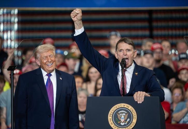 Former Navy SEAL officer Ed Gallrein speaks as President Donald Trump smiles while looking on during a visit to Verst Logistics on March 11, 2026, in Hebron, Ky. Trump is backing Gallrein in a challenge to Rep. Thomas Massie, R-Ky., in the November 2026...