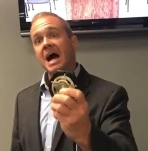 School board chairman Brent Hudson flashes his deputy's badge