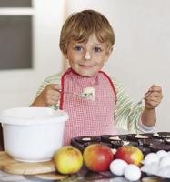 Funny blond kid boy baking apple cake indoors