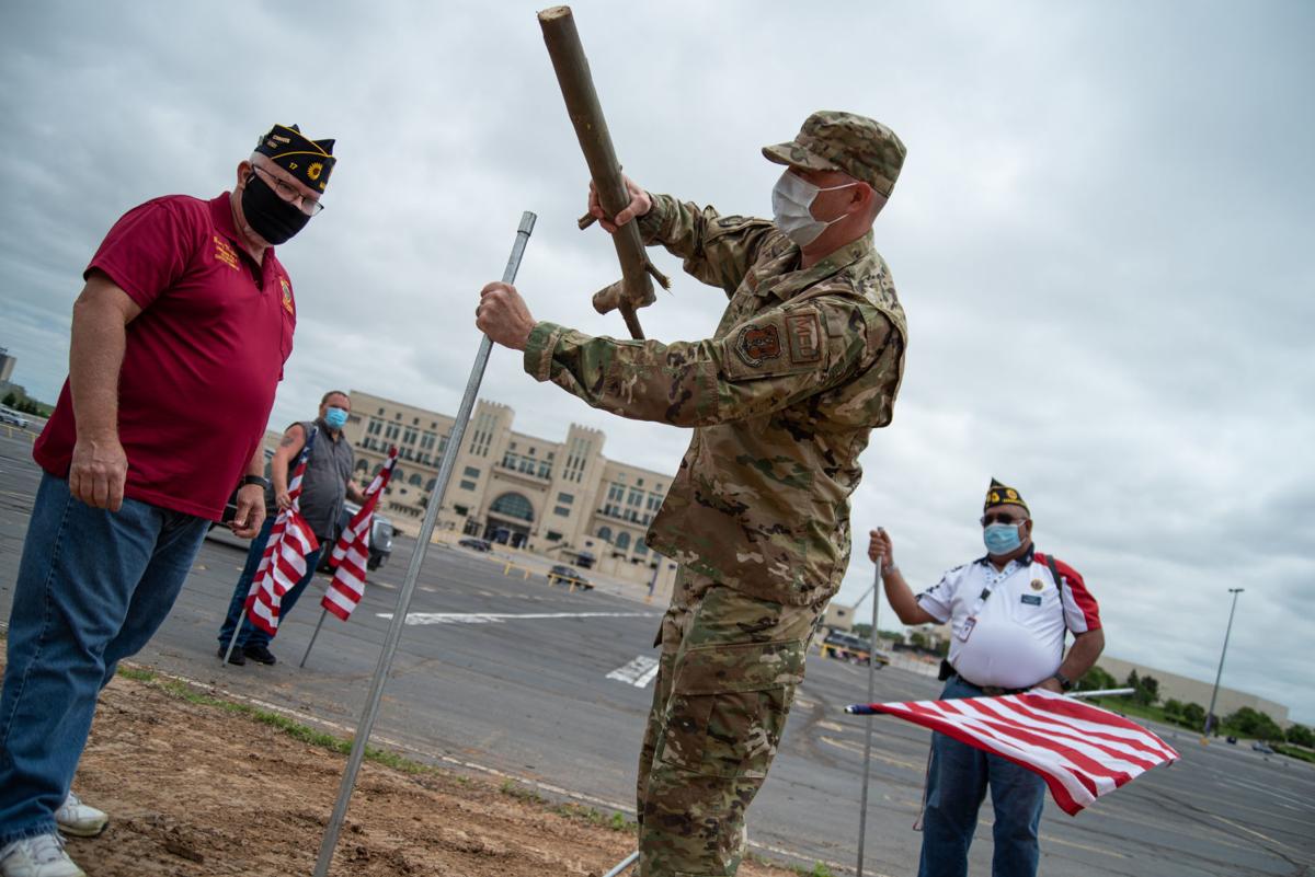 Senior Master Sergeant Wally Brannen hammers in a flag pole next to Barry Maples, left, and Matthew Burany, right, across from Ascension Via Christi Hospital before the National GuardÕs 190th Air Refueling Wing flies over on Tuesday.