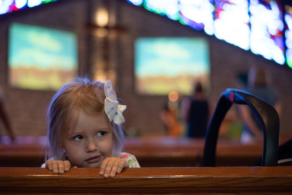 Victoria Allgeyer, 3, peeks over the church pew during worship at Peace Lutheran Church on Sunday.
