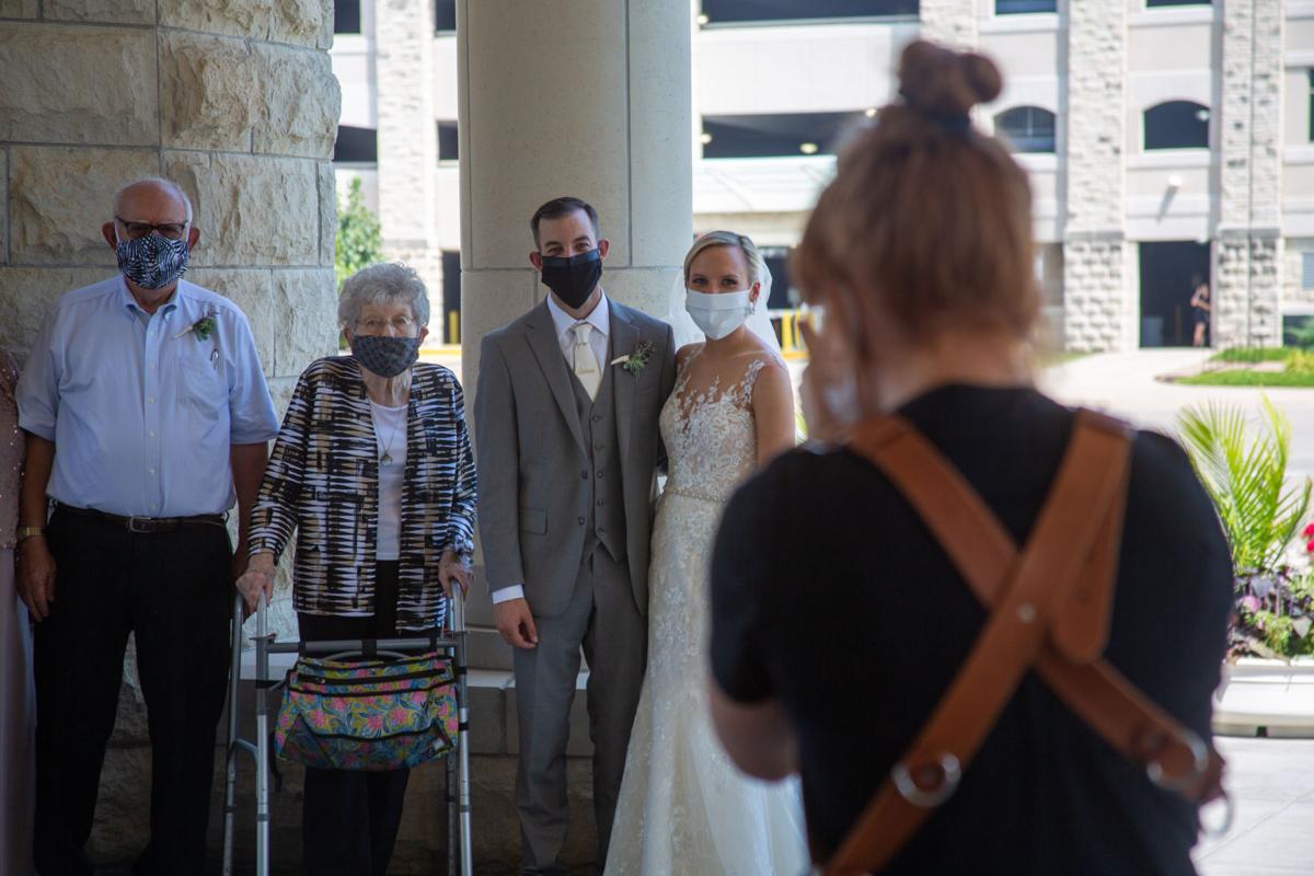 Bride Brittany Murrell with husband Matthew Lorson smile with famlily waring masks. Brittany Murrell and Matthew Lorson held reception at the Alumni center hosting a “drive by wedding” where guests could say their congratulations in the safety of their cars.
