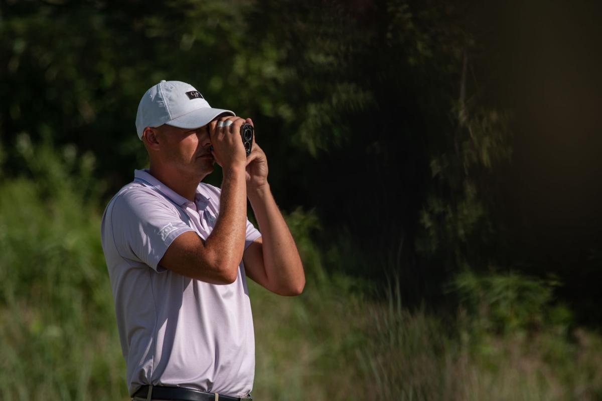 Jared Helin uses a distance measuring device before driving the ball on Hole 8.