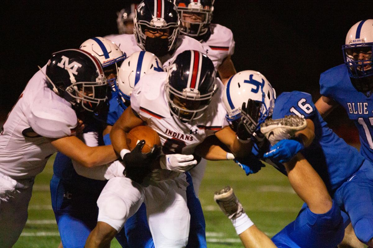 Running back Vincent Smith, junior, is surrounded by both teammates and opposing team as he attempts to move the ball forward. Manhattan High Indians went head to head against the Junction City Bluejays on Friday night at Al Simpler Stadium with a final score of Junction City 36, Manhattan 29.