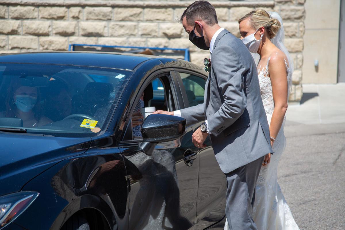 Brittany Murrell and Matthew Lorson walk to guests to hand them gifts at wedding reception. Brittany Murrell and Matthew Lorson held reception at the Alumni center hosting a “drive by wedding” where guests could say their congratulations in the safety of their cars.
