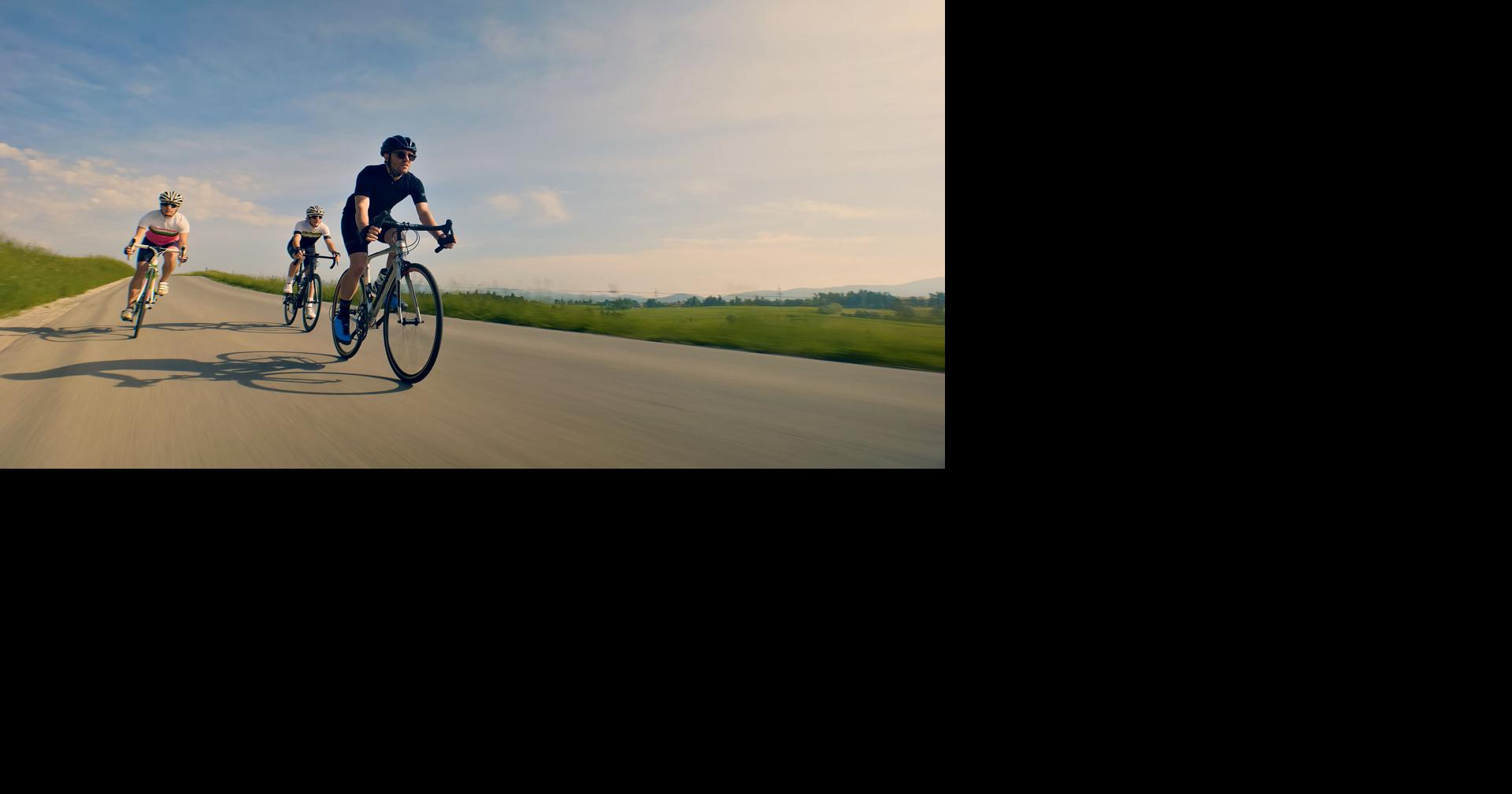 Three cyclists race down a scenic country road, showcasing their endurance and speed