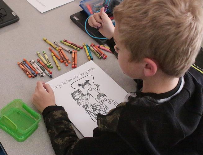 A second-grader gets set to work on his Caryville Cares Coloring Book.
