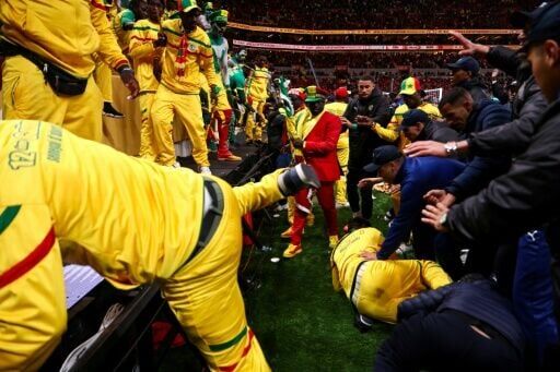 Angry Senegal fans are stopped from entering the pitch by security personnel