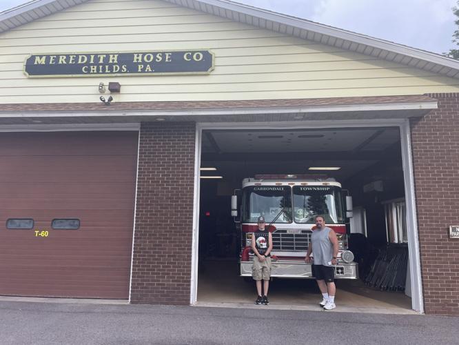 From left, Meredith Hose Company Junior Volunteer Carson Talarico and Chief Tony Aileo in front of one of the company’s trucks in the main garage.