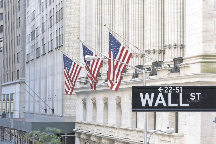 Wall Street sign with american flags and New York Stock Exchange in Manhattan, New York City, USA.