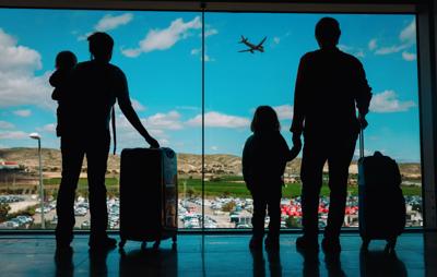 Family with kids and luggage looking at planes in airport