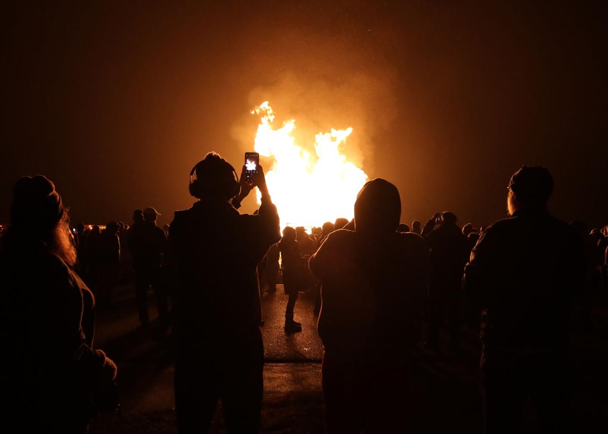 An attendee to the 2021 New Years Eve Bonfire captures a video of the burning structure shortly after it is set ablaze by members of the Charlestown Fire Department on Friday evening, December 31, 2021. The event, held yearly at Ninigret Park in Charles...