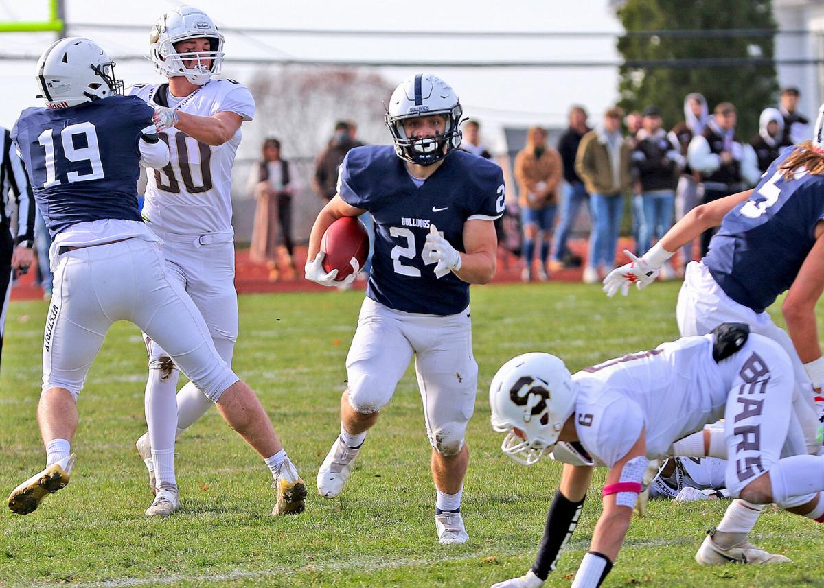 Senior Bulldogs captain Ben Gorman (19) blocks Stonington’s Patrick Obrey (80) while Zack Tuck (24) rushes for Westerly during the first half of the annual Westerly vs Stonington Thanksgiving Day football game played Thursday morning, November 25, 2021,...