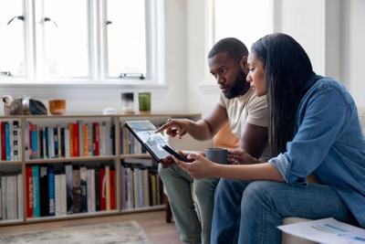 African American couple at home working on their financial planning using a tablet - home finances concepts